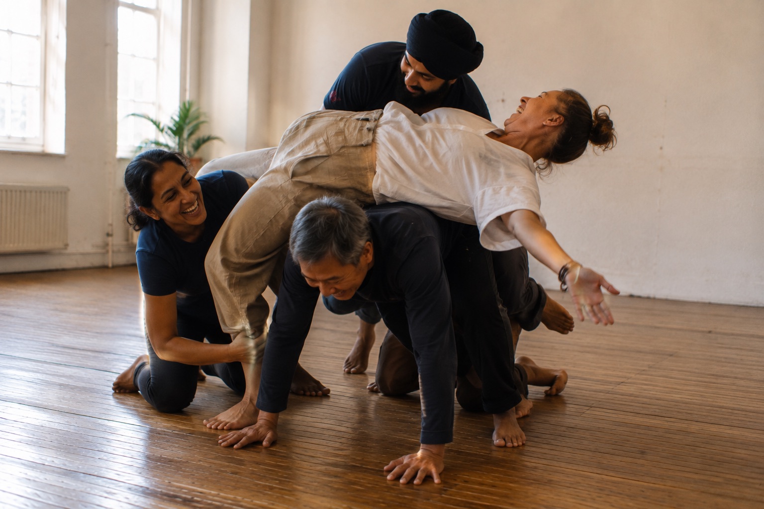 Four people stacked and balanced over each other mid-game, one lying back across the pile laughing, arms flung wide